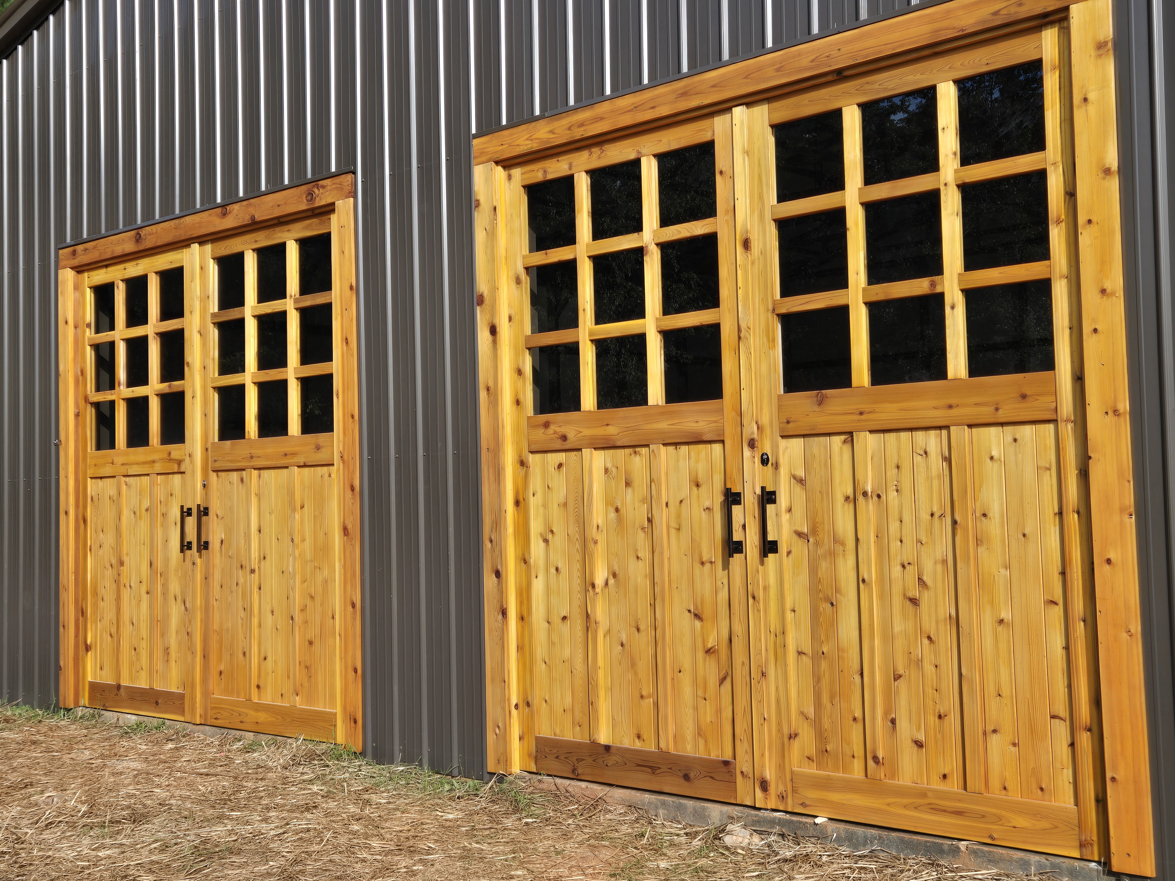 Handcrafted cedar barn doors with gridded windows on metal building by Old Wood Dynasty