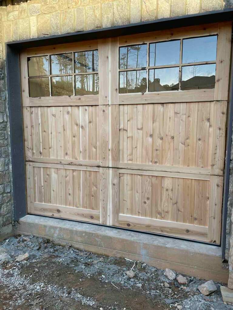 Handcrafted cypress carriage-style garage door with gridded windows on stone home by Old Wood Dynasty