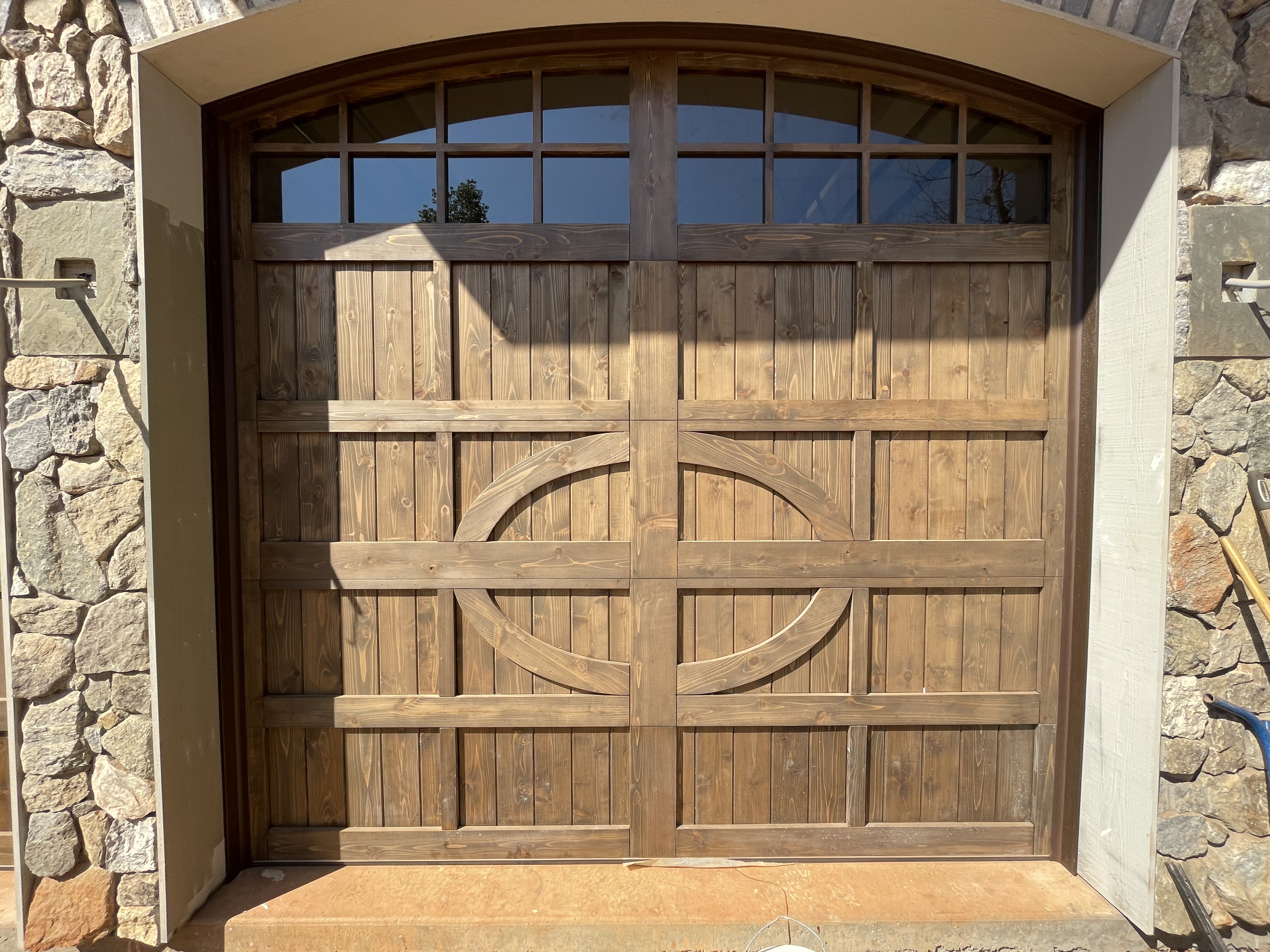 Custom ornate oval panel arched wooden garage door closeup by Old Wood Dynasty