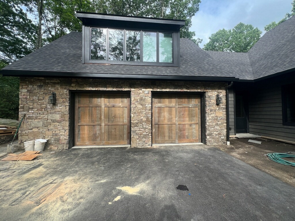 Handcrafted reclaimed wood double garage doors on stone facade home by Old Wood Dynasty