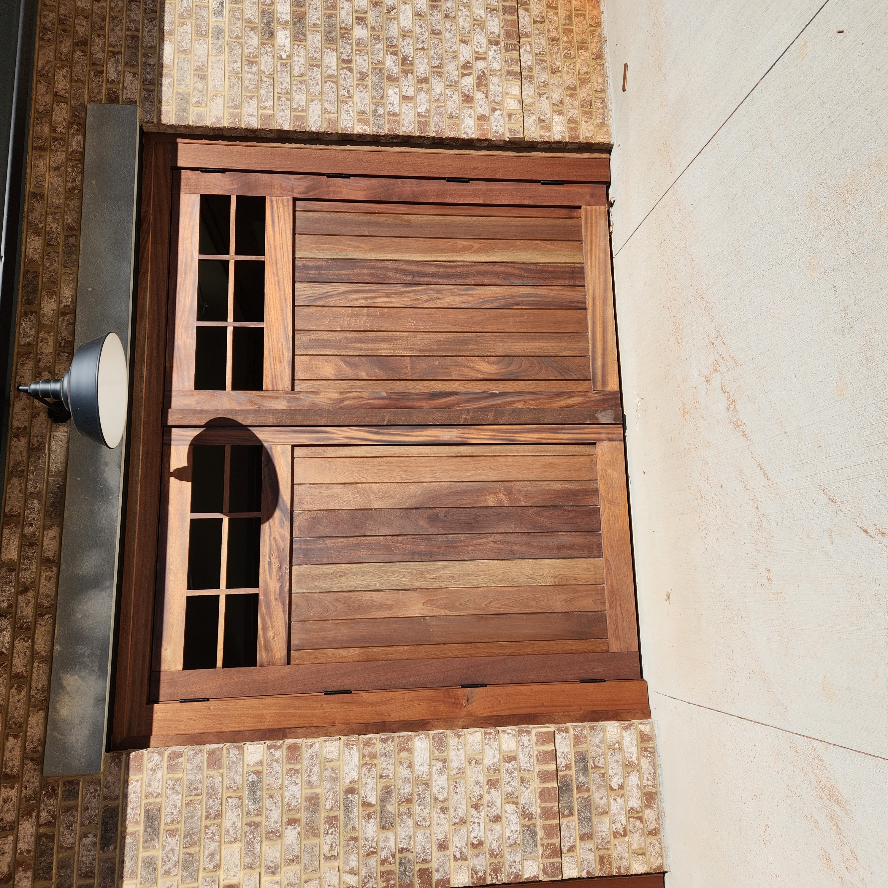 Custom sapele wood carriage-style garage doors on brick exterior by Old Wood Dynasty